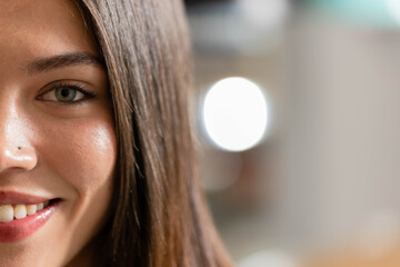African American woman smiling and facing camera in studio showing nose stud, hair, bokeh