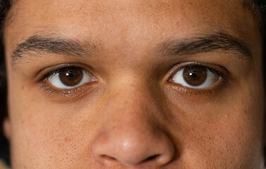 Male looking directly at camera in studio close-up, showing skin texture and camera highlights