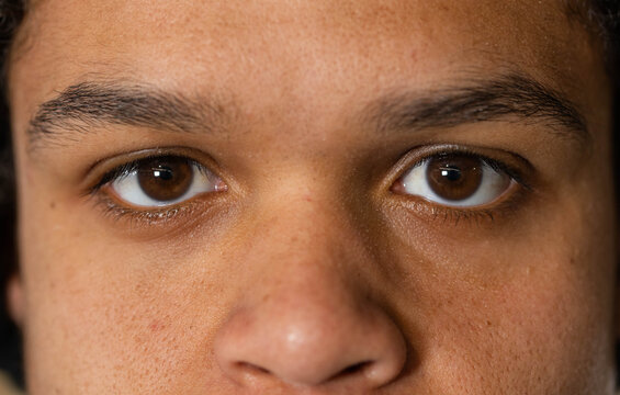 Male looking directly at camera in studio close-up, showing skin texture and camera highlights