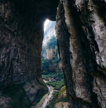 Aerial view of the karst landscape of Three Natural Bridges, where light filters through the towering stone arches, illuminating the lush valley below, Wulong, Chongqing, China.