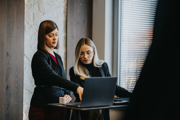 Two professionals collaborate over a laptop in a sleek office. A focused discussion unfolds as they review work on screen.