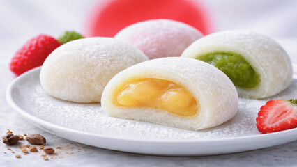 Assorted mochi with colorful fillings, delicate rice cakes served on white plate with fresh strawberries.