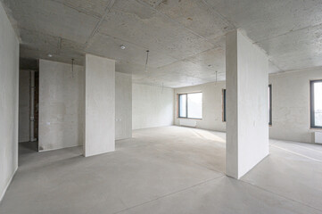 Naklejka premium spacious pre-finished room with exposed concrete ceiling and floor, plastered walls, structural columns, three large windows, minimal fixtures, ready for interior design.