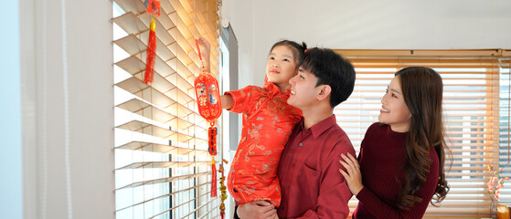 Asian father and daughter decorated house for Chinese New Year Celebrations. adorning their home...
