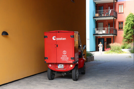 Red electric post van delivers the mail in the new cultural and urban center Bjorvika, Oslo, Norway