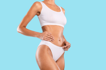 Close up shot of unrecognizable fit woman wearing lingerie posing isolated on blue studio...