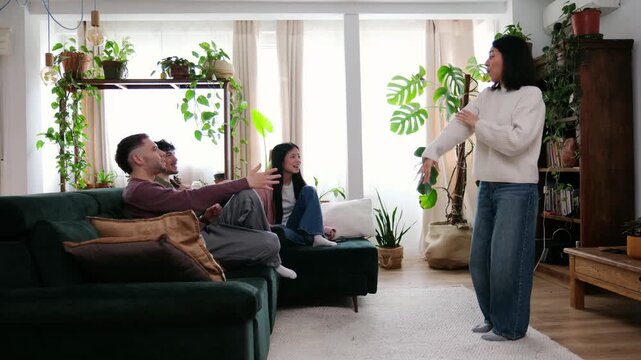 Group of diverse friends guessing words in a lively game of charades in the living room
