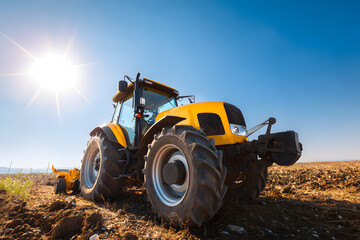 Tractor works in a field under a bright sun during daytime