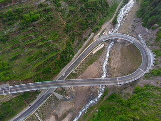 aerial view of winding highway bridge in mountain valley