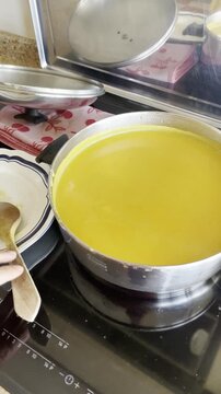 cocinando crema en cocina con cazuela y cuchara de madera