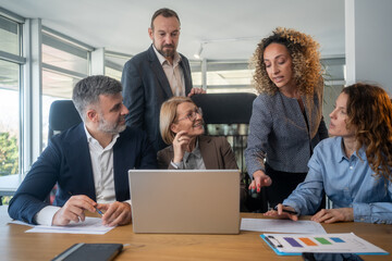 Casual meeting of smiling diverse business team analyzing financial data
