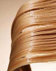 Hyper-realistic studio photography of hair textures, a lock of wet blond hair against light beige gradient background