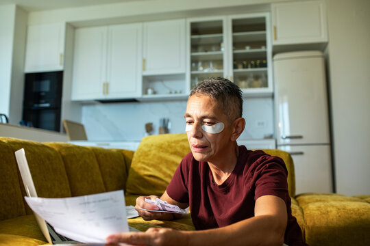Adult paying bills at home with eye patches