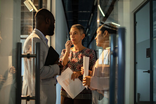 Business colleagues discussing project in office hallway