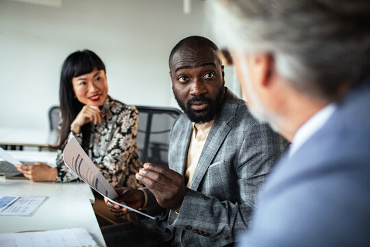 Colleagues discussing documents during meeting in modern office