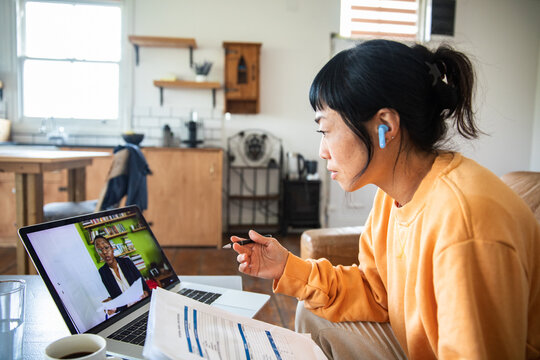 Woman on video call reviewing documents at home