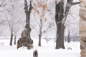 Ancient stone statue in snowy winter park
