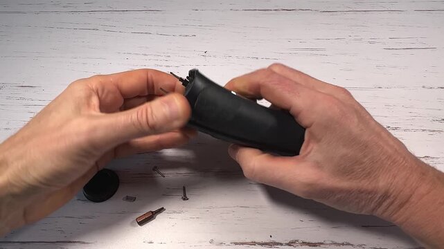 Disassembling a men's electric wireless razor and replacing old batteries - step 4 of 10, part of a series: removal of the razor head support and start removing the plastic from the handle 