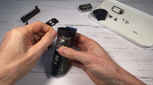 Disassembling a men's electric wireless razor and replacing old batteries - step 6 of 10, part of a series: removing screws of the plastic front part of the razor handle