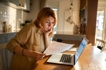 Concerned woman reviewing bills at home kitchen table