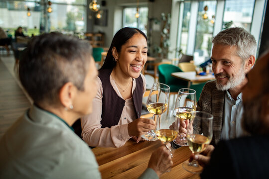Friends toasting with white wine at a modern restaurant