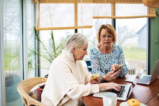 Senior women using smartphones and laptop at home