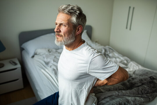 Middle-aged man with lower back pain in bedroom