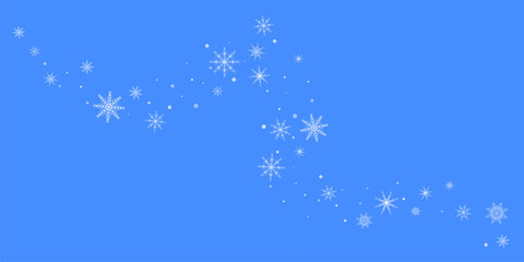 White delicate, lacy snowflakes are carried by the wind against a blue background. Christmas or New Year