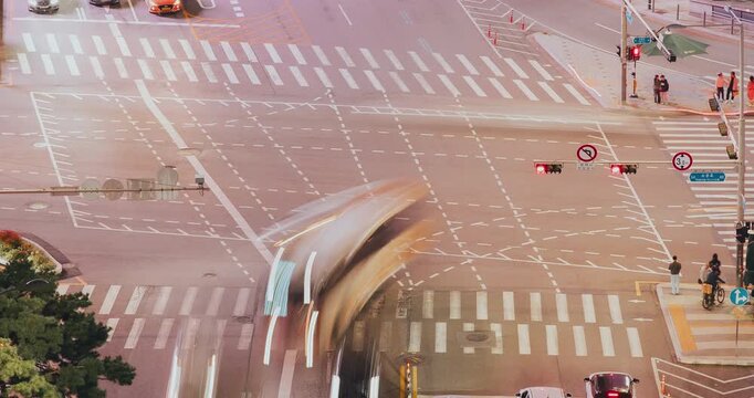 A vibrant urban intersection showcases traffic lights changing, vehicles navigating lanes, and pedestrians crossing streets in a bustling city environment. Time-lapse, Seoul, South Korea