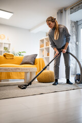 Fototapeta premium Woman vacuuming living room floor for clean home