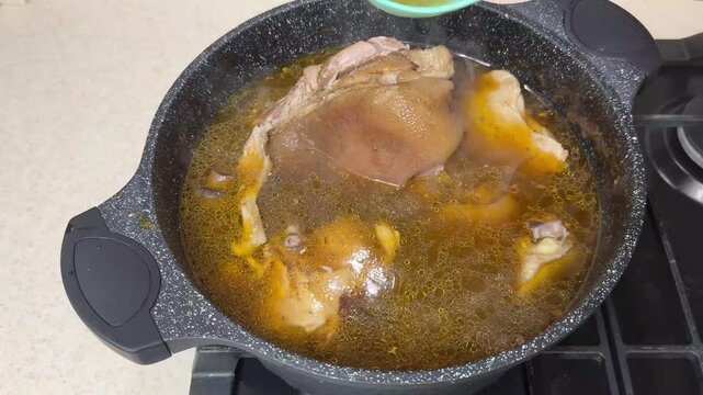 Basting Pork Shank with Fatty Broth and Turning Meat in Black Pot. Chef Using Ladle for Rich Soup with ASMR Sound. Tender Knuckle Cooking Process.