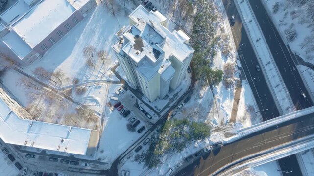 High-altitude aerial view of a city district with buildings and roads covered in snow