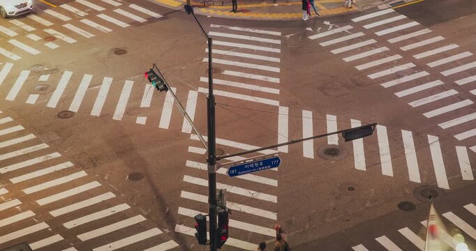 An urban intersection scene at night displays traffic signals, crosswalks, and vehicles in motion, capturing the lively essence of city life. Time-lapse, Seoul, South Korea