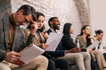 Professional job applicants waiting together in an office interview room, expressing anticipation, stress, and hope for career opportunity.