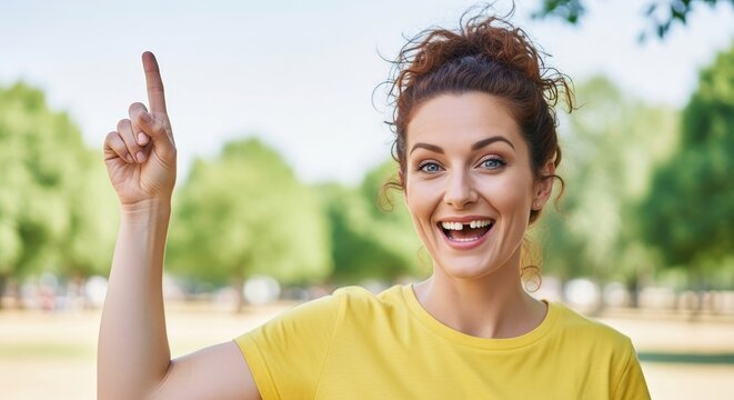 Enthusiastic woman with a missing tooth joyfully pointing upwards outdoors in the sun