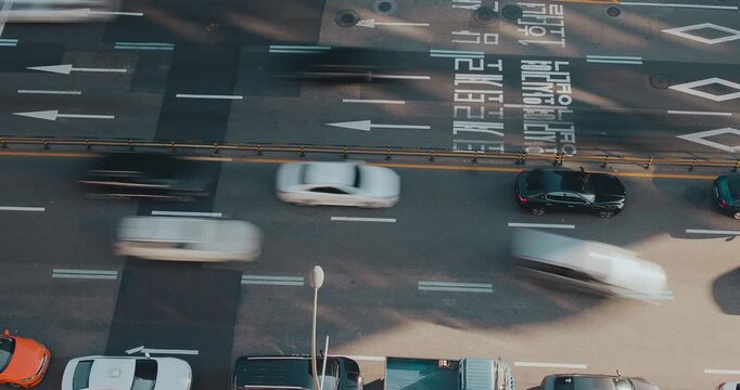 Vehicles move continuously along a bustling street, highlighting the rhythm of urban traffic and the interplay of cars and road signs. Time-lapse, Seoul, South Korea
