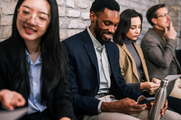 Diverse group of people sitting in an office waiting room before a job interview, showing career opportunity, recruitment process, and professional business environment.