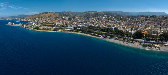 Obraz premium Aerial panoramic view of Reggio Calabria, a city overlooking the Mediterranean Sea in southern Italy. It has a long waterfront overlooking the crystal-clear, turquoise sea. It's a sunny summer morning