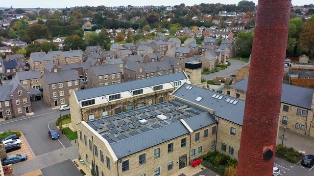 Aerial drone footage of the town of Yeadon in Leeds West Yorkshire UK Showing a brand new housing estate with rows of houses next to an old converted industrial mill buildings and original chimney