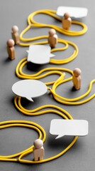 Wooden toy figures form a circle with yellow rope and speech bubbles to represent communication and connection among team members.