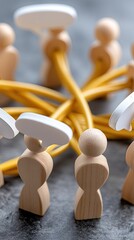 Wooden toy figures form a circle with yellow rope and speech bubbles to represent communication and connection among team members.