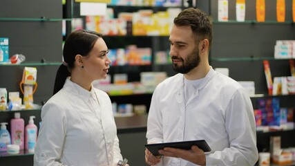 Two pharmacists collaborating in a pharmacy using digital tablet