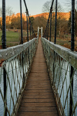 Obraz premium Narrow wood and iron suspension bridge crossing the river Wharfe in the Yorkshire Dales National Park