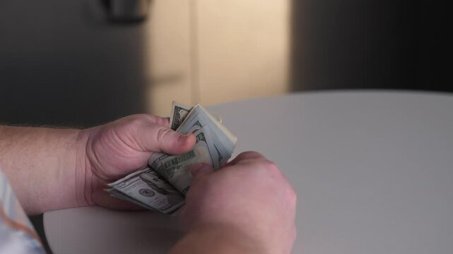 Careful Cash Handling In Quiet Setting, Man Organizing Envelopes With Precise Movements, Person Methodically Preparing Payment Packets Beneath Gentle Illumination In Subdued Environment