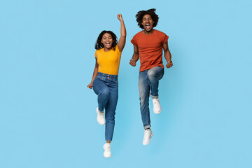 Positive young african american couple beautiful man and woman in casual celebrating success on...