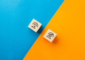 Two wooden blocks with online and offline icons on a split blue and orange background. Concept of digital connectivity, internet access, social media addiction