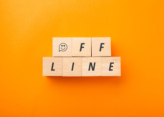 Wooden blocks spelling the word OFFLINE with a smiley face icon on a bright orange background. Top view concept for digital detox, mental health, social media break, and work-life balance.