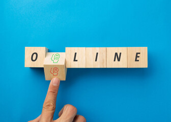 A finger flips a wooden block to choose between a happy or sad face icon within the word ONLINE on a blue background. Concept for mental health, social media impact, and digital wellbeing balance.