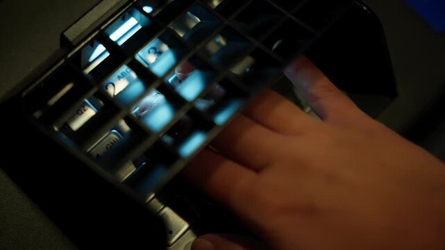 Close-up of a hand on a biometric fingerprint scanner under blue illumination, capturing detailed ridge patterns for secure identification, authentication, and access control.