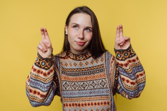 Young woman in a colorful sweater making air quotes against a yellow background.